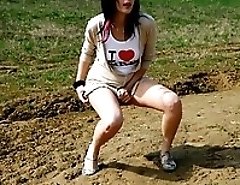 Brunette wets the sand under her feet with her pee
