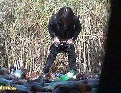 Woman in black pees on trash outdoors