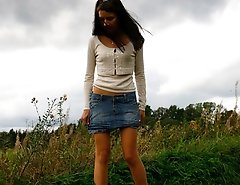 Cute brunette babe pisses up a storm in the field